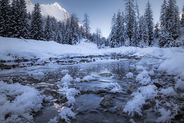 gaistal-natur-im-winter-gefrorener-flusslauf-mit-beschneiten-baeumen-und-hohe-wand-1