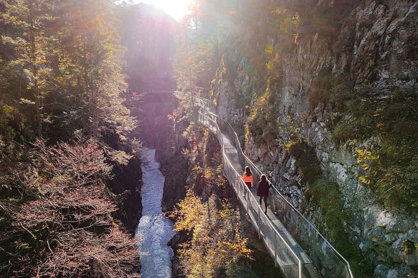 geisterklamm-im-herbst-drohnenaufnahme-zwei-frauen-laufen-auf-dem-steg-1