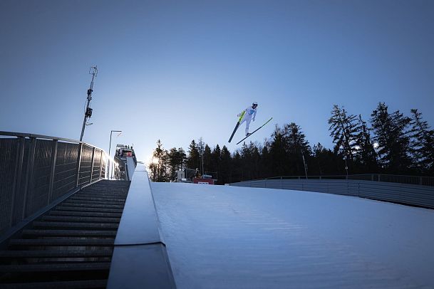 nordic-triple-2024-tag-2-skispringer-beim-absprung-weitwinkel-mit-sonne-1