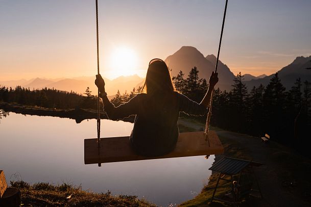 person-schaukelt-bei-sonnenuntergang-am-kaltwassersee-1