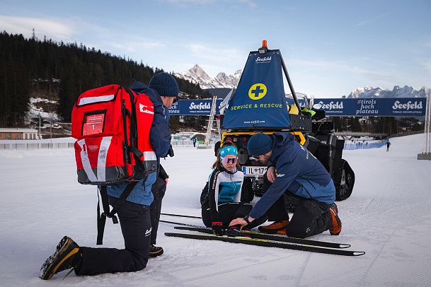 seefeld-loipenservice-erste-hilfe-langlaeuferin-gestuertzt-helfer-mit-grossem-erste-hilfe-rucksack-1