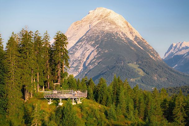 sonnenaufgang-aussichtsplattform-bruschkopf-drohnenaufnahme-zoomaufnahme-paar-steht-am-gelaender-der-plattform-blick-zur-hohen-munde-1