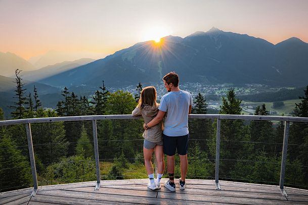 sonnenaufgang-aussichtsplattform-bruschkopf-paar-steht-am-gelaender-der-plattform-aufnahme-von-hinten-paar-schaut-sich-an-1