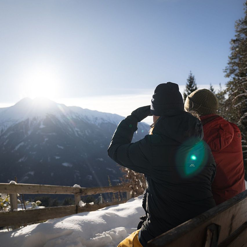 Winterwandern Paar Möserer See Paar sitzt auf Bank und blickt in Inntal Frau hebt Hand