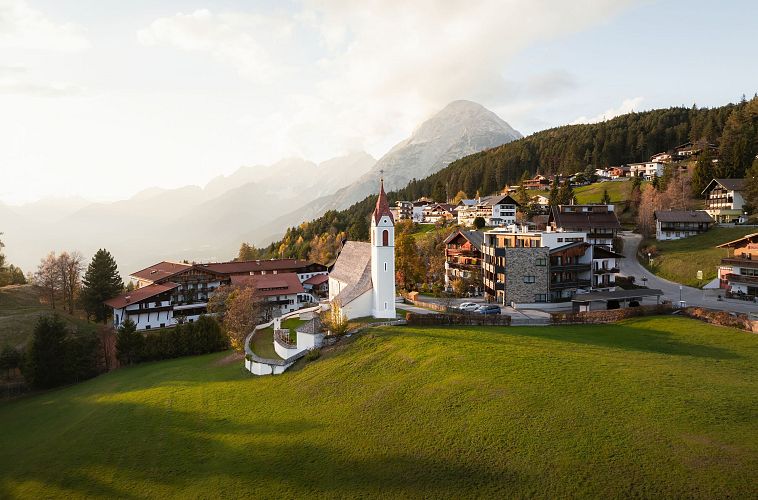 drohnenaufnahme-moesern-im-herbst-kirche-mit-hohe-munde-bei-sonnenuntergangsstimmung