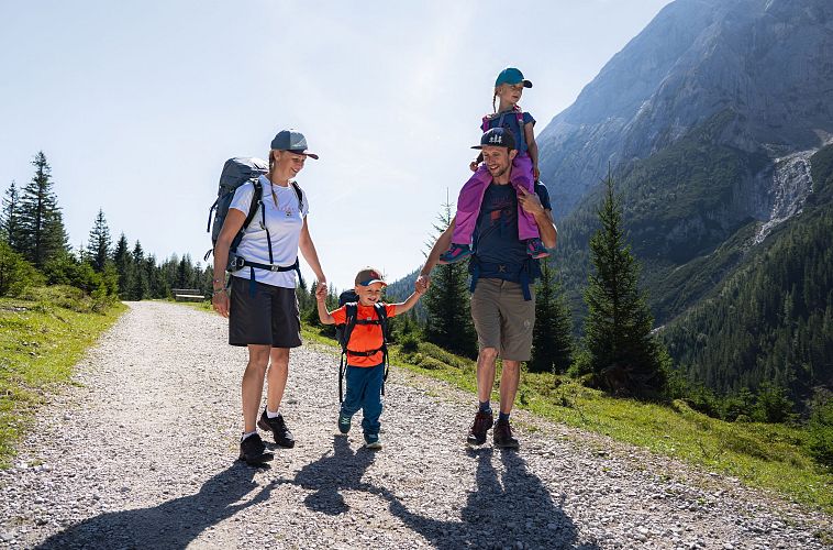 familien-weitwanderung-im-gaistal-familie-auf-breitem-wanderweg-tochter-auf-dem-schultern-des-vaters