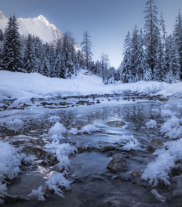 gaistal-natur-im-winter-gefrorener-flusslauf-mit-beschneiten-baeumen-und-hohe-wand-1