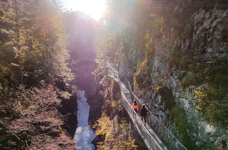 geisterklamm-im-herbst-drohnenaufnahme-zwei-frauen-laufen-auf-dem-steg