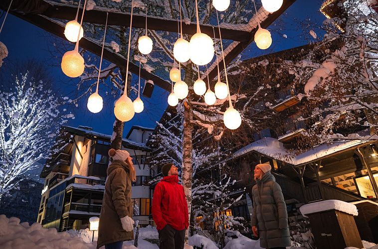 lichterpark-seefeld-drei-menschen-schauen-auf-lichterkugelinstallation