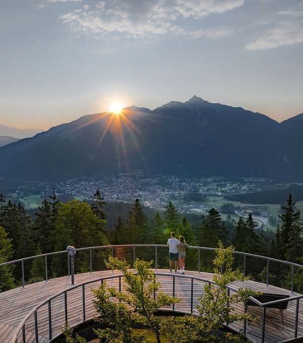 sonnenaufgang-aussichtsplattform-bruschkopf-drohnenaufnahme-paar-steht-am-gelaender-der-plattform-sonnenstern-ueber-seefelder-spitze-3