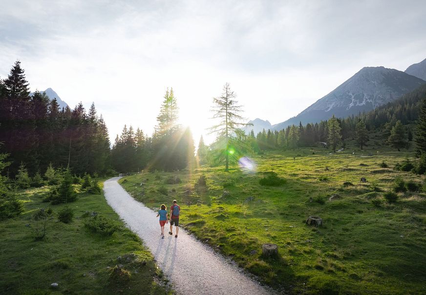 sub1-drohnenaufnahme-wanderung-im-gaistal-im-sommer-paar-auf-wanderweg-bei-tiefstehender-sonne