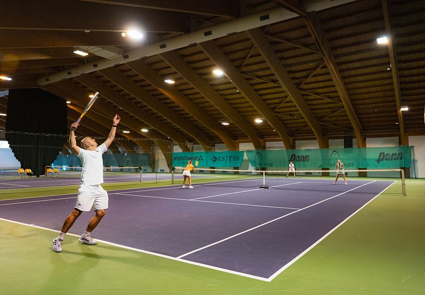 sub1-indoor-tennisanlage-seefeld-doppel-mann-schlaegt-auf-ball-in-der-luft