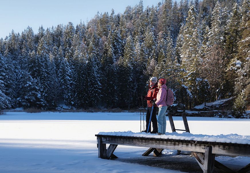 sub1-winterwandern-in-der-region-seefeld-mann-und-frau-am-moeserer-see-stehen-auf-steg