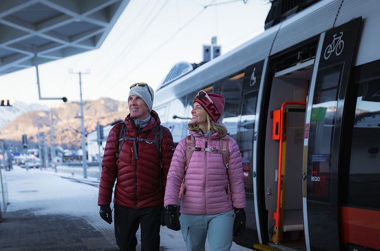 winterwandern-in-der-region-seefeld-portrait-mann-und-frau-kommen-in-seefeld-am-bahnhof-an-1