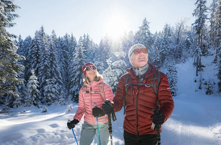 winterwandern-in-der-region-seefeld-wildmoos-mann-und-frau-laufen-durch-den-wald-im-wildmoos-und-blicken-in-die-baeume-nahaufnahme-von-vorne-1-1