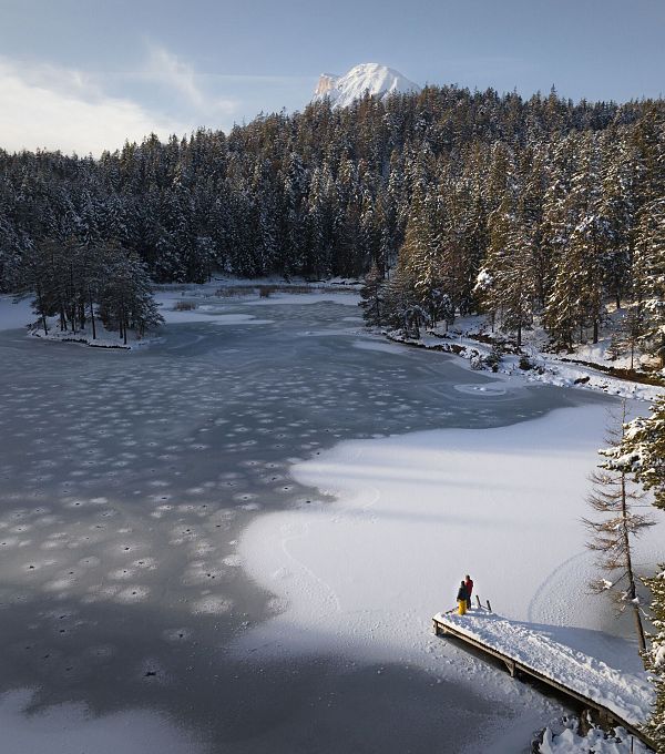 winterwandern-paar-moeserer-see-drohnenaufnahme-paar-steht-am-steg-blick-richtung-huhe-munde-1