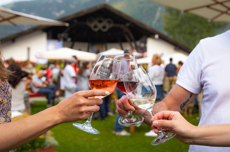 winzerfest-seefeld-2024-anstossen-mit-verschiedenen-weinen-vor-der-festkulisse