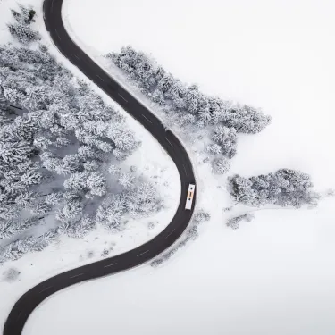 Mobilität im Winter in der Region Seefeld_Drohnenaufnahme Bus fährt von Seefeld nach Leutasch_Vogelperspektive in Kurve